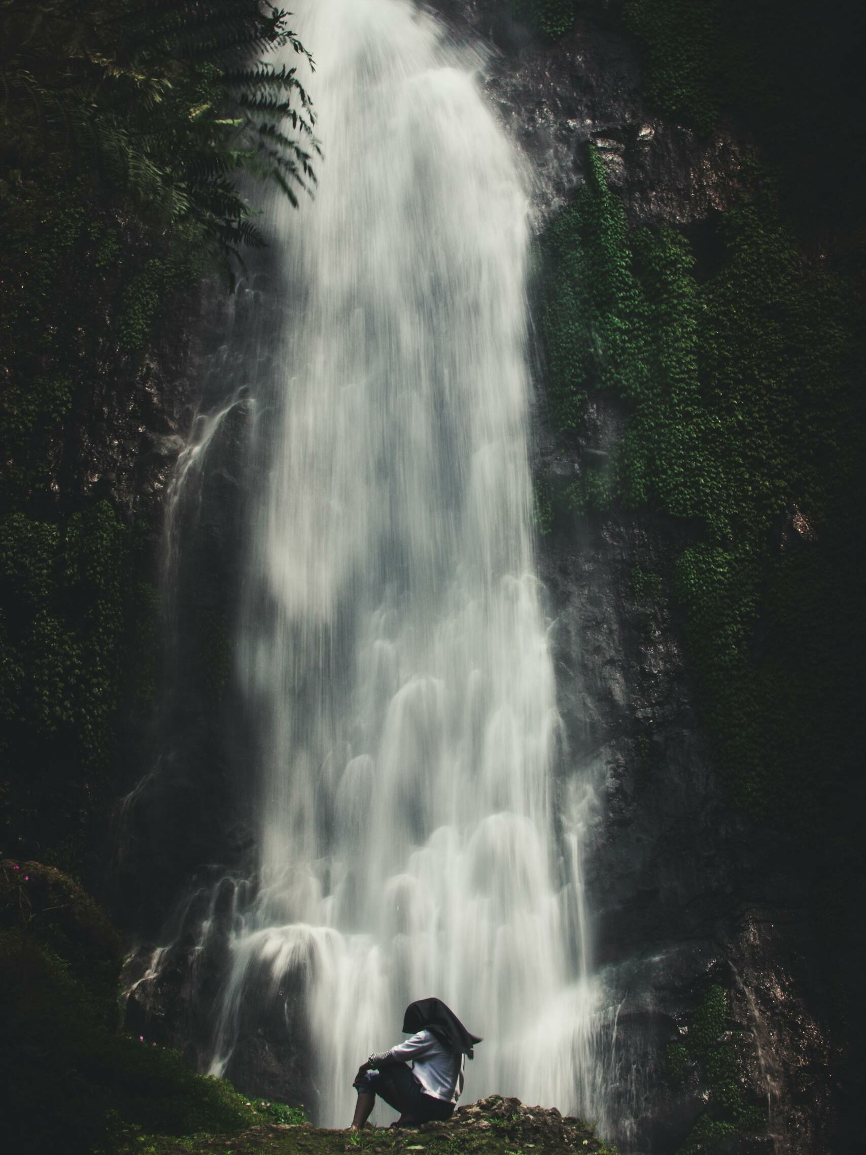 Photo of Man Sitting Near Waterfalls